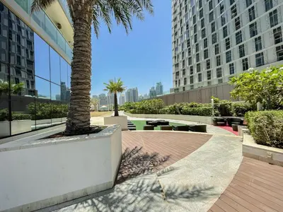 a palm tree in a courtyard with tall buildings at Exquisite 1 Bedroom Sea View with Lavish Amenities in Dubai