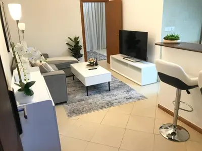 a living room with a couch and a tv at Cozy one bedroom close to beach and metro station in Dubai