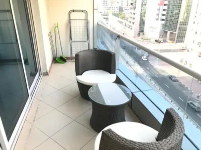 a balcony with two chairs and a table on a building at Cozy one bedroom close to beach and metro station in Dubai