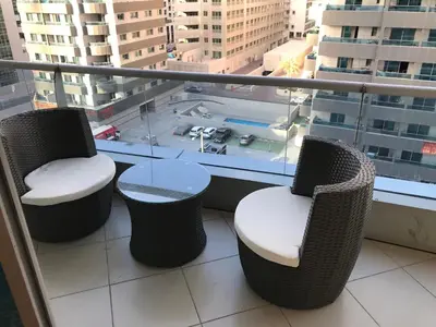 a balcony with two chairs and a table and a window at Cozy one bedroom close to beach and metro station in Dubai