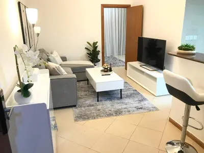 a living room with a couch and a tv at Cozy one bedroom close to beach and metro station in Dubai