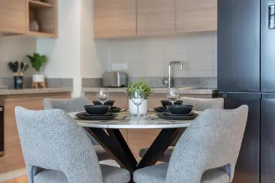 a kitchen with a table with chairs and a refrigerator at Sleek and Modern Stay in Dubai Hills in Dubai