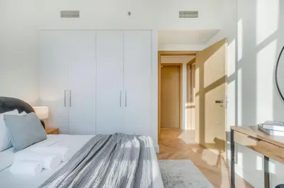 a white bedroom with a bed and a mirror at Sleek and Modern Stay in Dubai Hills in Dubai