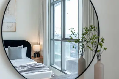 a mirror in a room with a bed and a window at Sleek and Modern Stay in Dubai Hills in Dubai