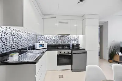 a white kitchen with a sink and a stove at Dubai Aykon city in Dubai