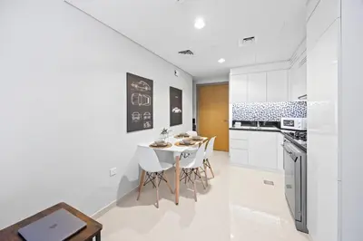 a kitchen with white cabinets and a table and chairs at Dubai Aykon city in Dubai