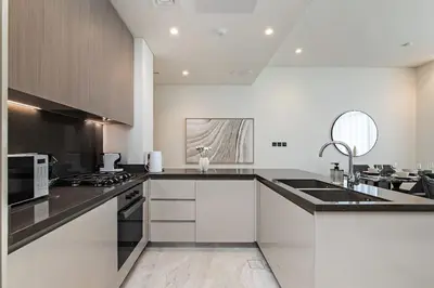 a kitchen with white cabinets and a black counter top at High-Rise 1BR Apartment with Burj Khalifa view in Dubai