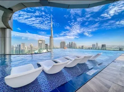 a pool with white chairs in the middle of a city skyline at Stylish 2BR Apt in 5 Star Hotel with Burj Khalifa Views in Dubai