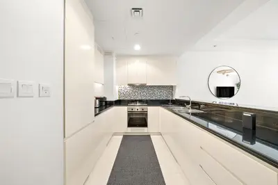 a white kitchen with white cabinets and a sink at Stylish 2BR Apt in 5 Star Hotel with Burj Khalifa Views in Dubai