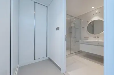 a white bathroom with a shower and a sink at Luxury 2BR Apt with Pool, Gym & Sea Views in Dubai