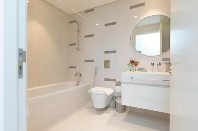 a white bathroom with a tub and a toilet and a sink at Luxury 2BR Apt with Pool, Gym & Sea Views in Dubai