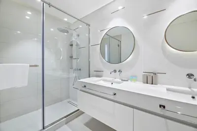 a white bathroom with a sink and a shower at Luxury 2BR Apt with Pool, Gym & Sea Views in Dubai
