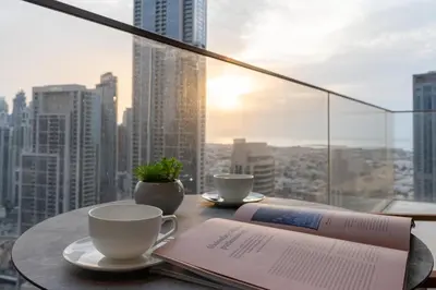 a table with two coffee cups and a book on it at Ultimate Stay Luxurious Address Opera 2BR Next to Burj Khalifa and Dubai Mall Large Balcony with Stunning Views in Dubai