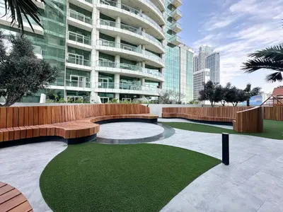 a park with a bench and grass in front of a building at Trophy-Lux 1BR Jacuzzi Suite Busbay W Big Balcony in Dubai