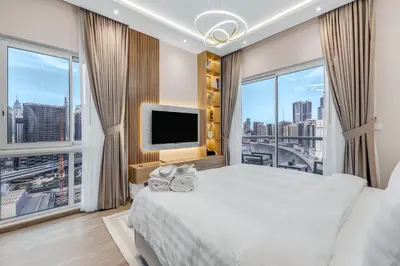 a bedroom with a large bed and a tv at Burj Khalifa & Canal Views at Mayfair Tower in business bay - Luxurious 1BDR Apartment in Dubai