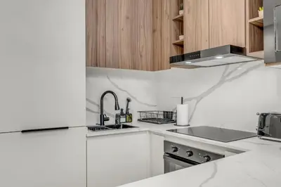 a white kitchen with a sink and a stove at Burj Khalifa & Canal Views at Mayfair Tower in business bay - Luxurious 1BDR Apartment in Dubai