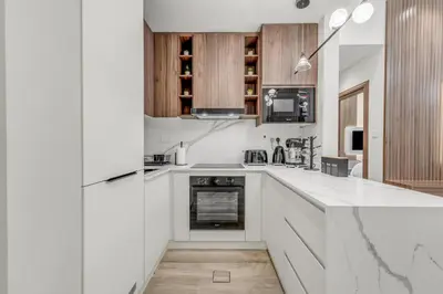 a kitchen with white counter tops and wooden cabinets at Burj Khalifa & Canal Views at Mayfair Tower in business bay - Luxurious 1BDR Apartment in Dubai