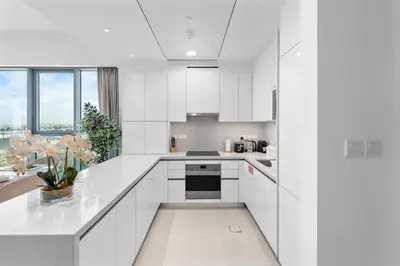 a white kitchen with white cabinets and a window at Magnificent - New 1BR in Canal Front Residences in Dubai