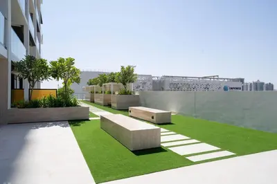 a rooftop garden with benches and grass on a building at Stylish 1br With Garden View In Jvc in Dubai