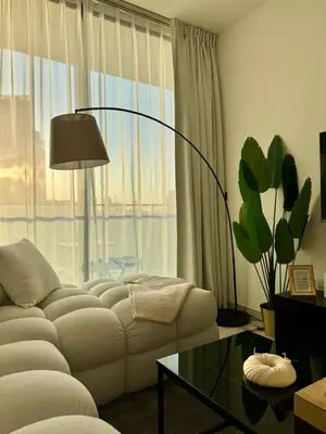 a living room with a white couch and a large window at Stylish 1br With Garden View In Jvc in Dubai
