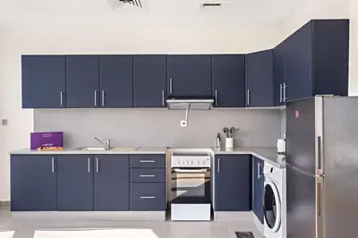 a kitchen with blue cabinets and a refrigerator at Silkhaus Chic Studio at Barsha Heights in Madison in Dubai
