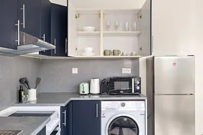 a kitchen with a washer and a white refrigerator at Silkhaus Chic Studio at Barsha Heights in Madison in Dubai