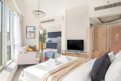 a white bedroom with a large bed and a tv at Silkhaus Chic Studio at Barsha Heights in Madison in Dubai