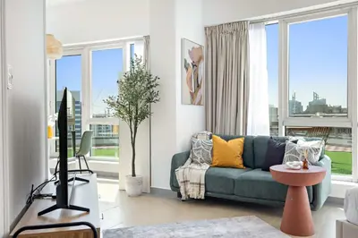 a living room with a blue couch and a tv at Silkhaus Cozy Studio at Madison in Barsha Heights in Dubai