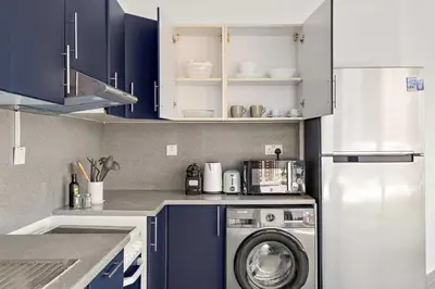 a kitchen with a washing machine and blue cabinets at Silkhaus Large Studio in Madison near Barsha Heights in Dubai