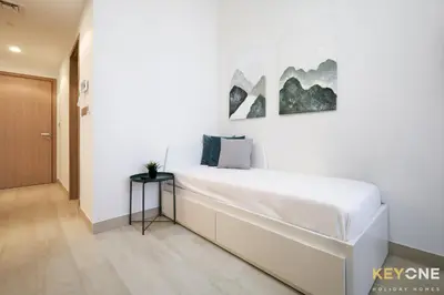a white bedroom with a large bed and a table at Modern Elegance Studio in Azizi Riviera in Dubai
