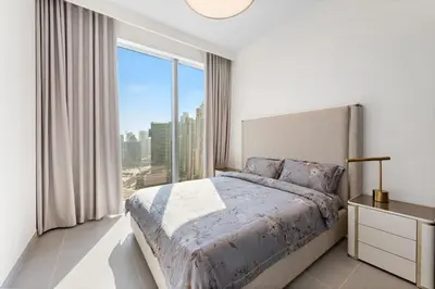 a bedroom with a bed and a large window at Forte Tower 1 in Dubai
