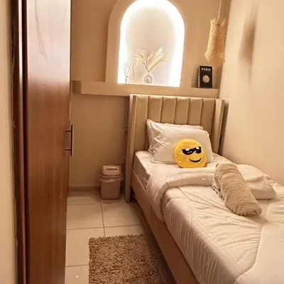 a bedroom with a bed with a smiley face pillow on it at Adaz Homes in Dubai