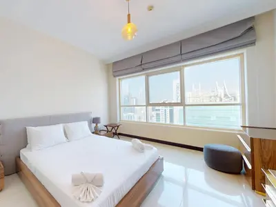 a bedroom with a white bed and a large window at Spacious Duplex 4BR with Maids Room in Dubai