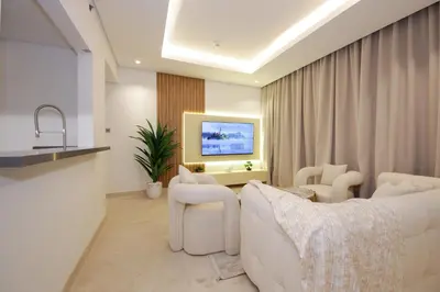 a living room with white furniture and a tv at Luxury 2BHK Plus Maid's Room The Sterling West Near Dubai Mall in Dubai