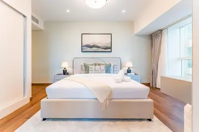 a white bedroom with a large bed and a window at Upgraded 2BR with Partial Sea and City Views Near the Beach, Elite Residence, Dubai Marina by Deluxe Holiday Homes in Dubai