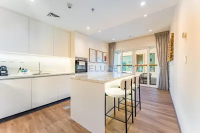 a kitchen with white cabinets and bar stools at Upgraded 2BR with Partial Sea and City Views Near the Beach, Elite Residence, Dubai Marina by Deluxe Holiday Homes in Dubai