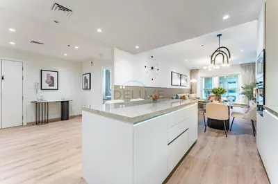 a kitchen and living room with white cabinets and a dining room at Renovated 1BR with Partial Sea and City Views Close to the Beach, Elite Residence, Dubai Marina by Deluxe Holiday Homes in Dubai