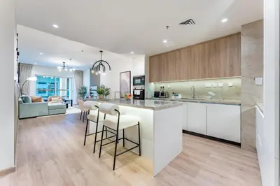 a kitchen with white cabinets and a bar with stools at Renovated 1BR with Partial Sea and City Views Close to the Beach, Elite Residence, Dubai Marina by Deluxe Holiday Homes in Dubai