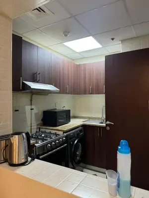 a kitchen with wooden cabinets and a stove top oven at Cozy 1Bed Sports city in Dubai