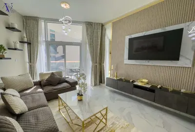 a living room with a couch and a television on a wall at Luxurious 2-Bedroom Haven in Dubai