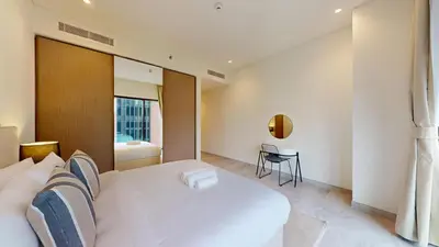a bedroom with a large white bed and a table at Peninsula - Modern Two Bedroom in Business Bay in Dubai