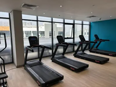 a gym with several treadmills in a room with windows at Meydan Riviera Midtown Comfort Studio in Dubai
