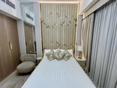 a bedroom with a large white bed and a chair at Meydan Riviera Midtown Comfort Studio in Dubai