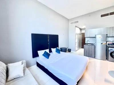 a bedroom with a large white bed and a kitchen at Al Manara Classic Luxe Studio in Dubai