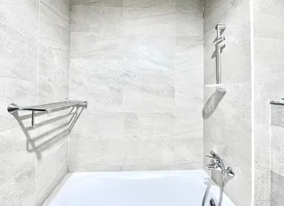 a white bathroom with a shower and a tub at Al Manara Classic Luxe Studio in Dubai