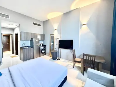 a bedroom with a white bed and a kitchen at Al Manara Classic Luxe Studio in Dubai