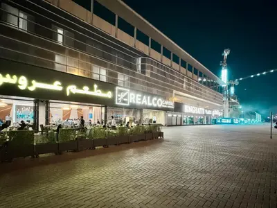 a large building with people sitting outside of it at night at Al Manara Classic Luxe Studio in Dubai