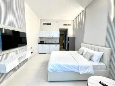 a white bedroom with a bed and a kitchen at Al Manara Premium Lux Studio in Dubai