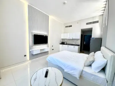 a white bedroom with a bed and a table at Al Manara Premium Lux Studio in Dubai