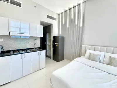 a white bedroom with a bed and a kitchen at Al Manara Premium Lux Studio in Dubai